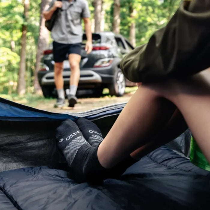 person sitting in tent in the woods wearing black wicked comfort merino wool performance sock 1/4 crew length | OS1st